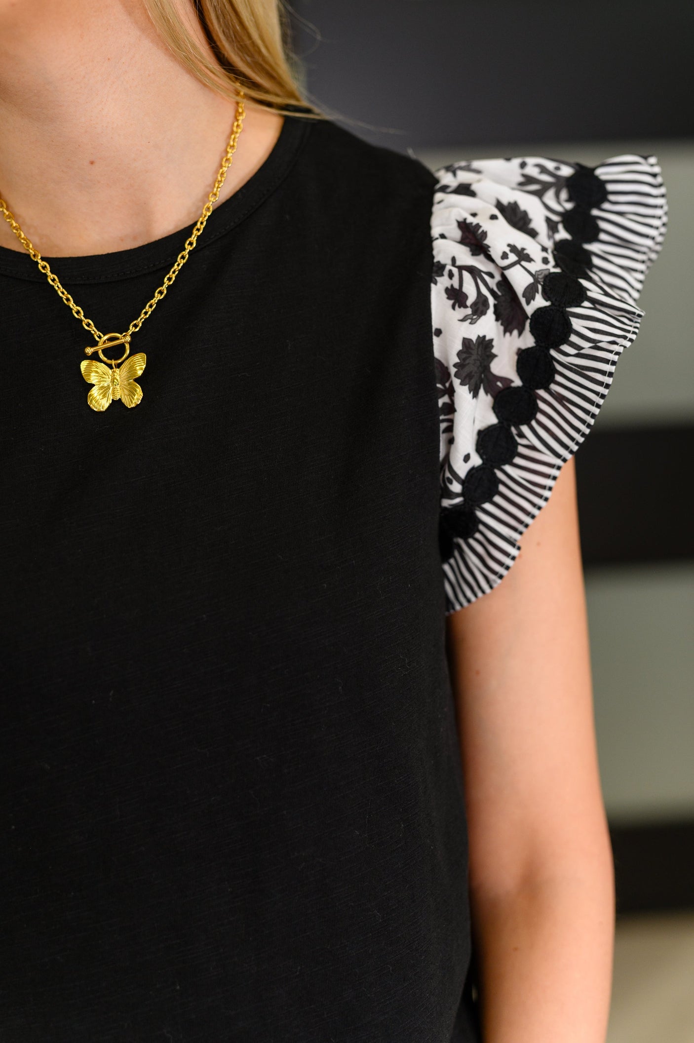 Top negro con mangas onduladas en contraste